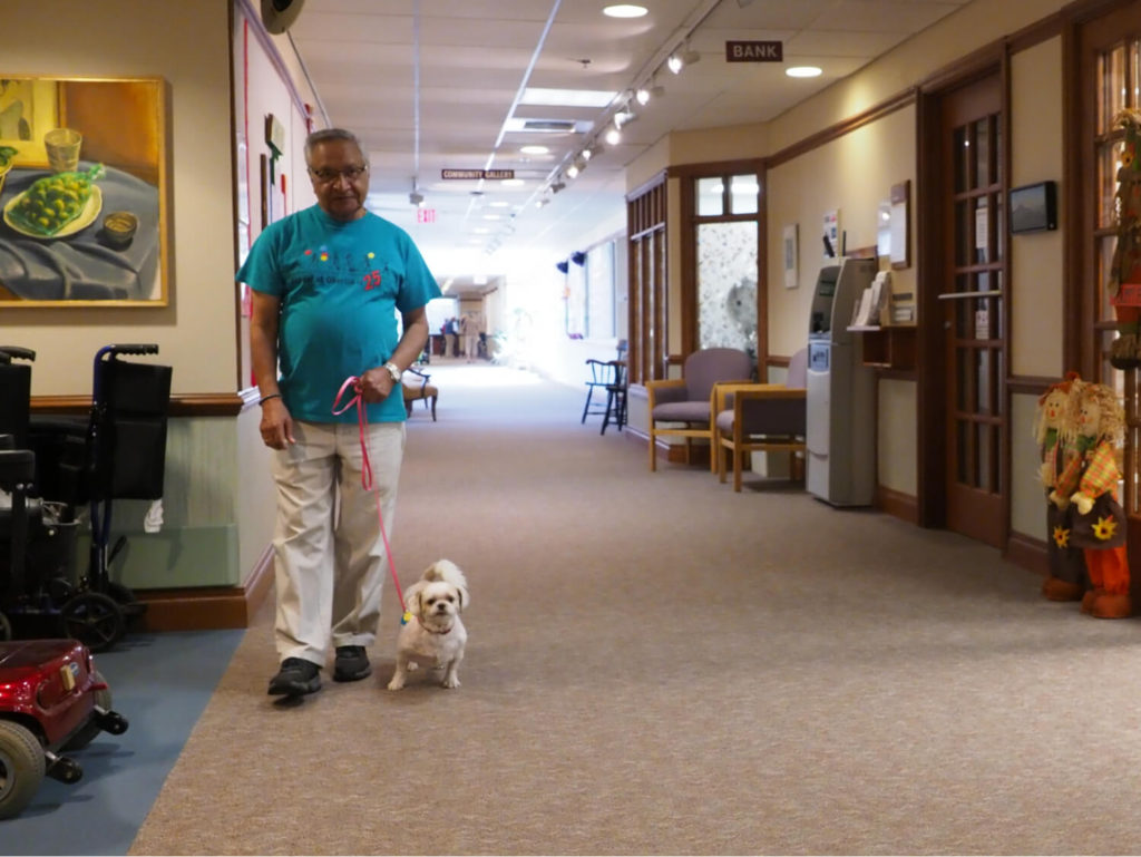 man walking small dog down hallway