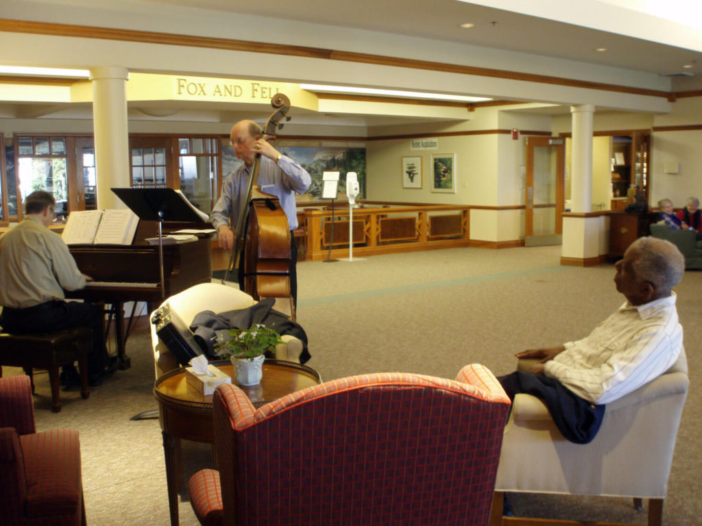 man playing piano, man playing double base, and man listing in chair 
