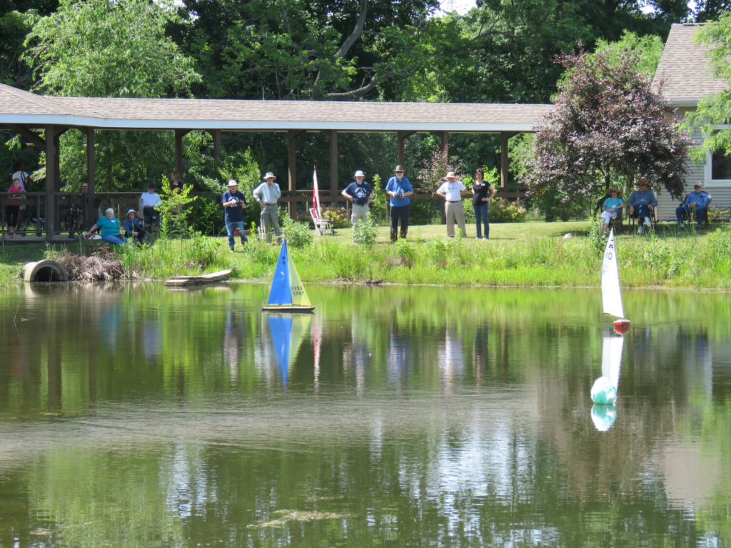 group of people watching small boats on pond