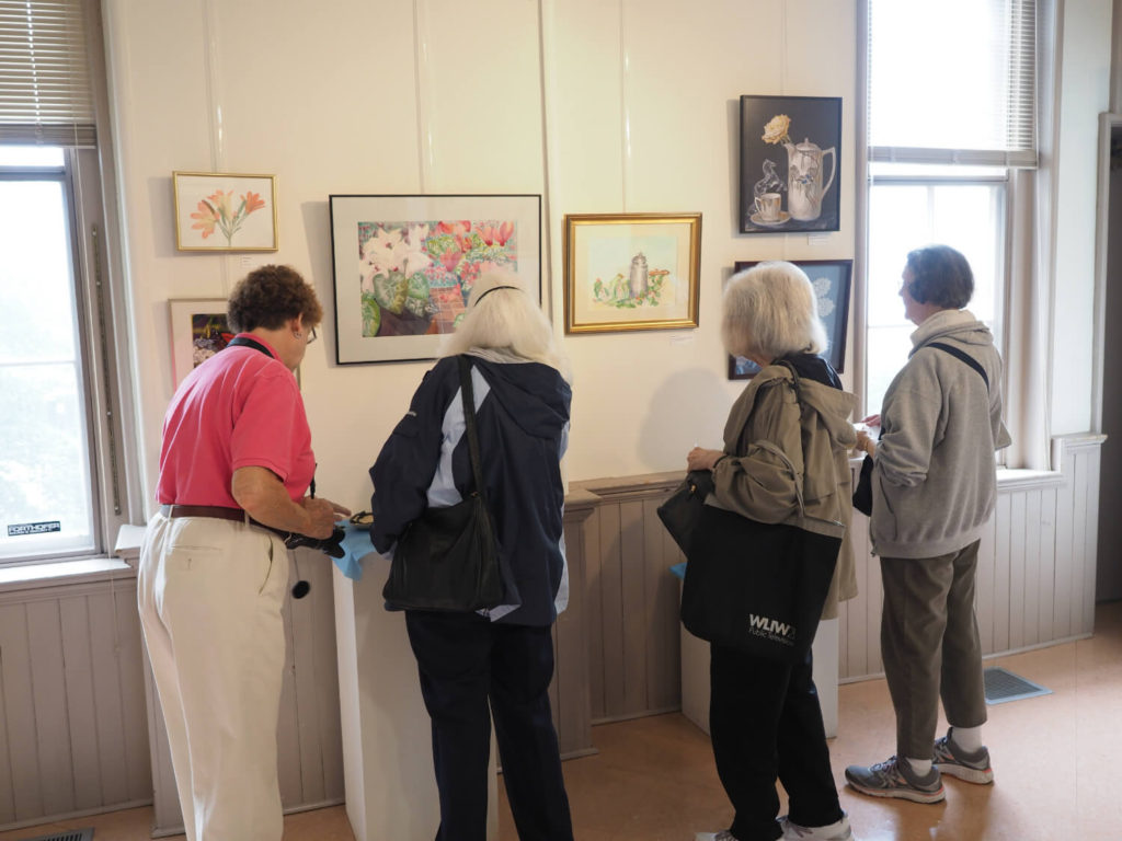 four woman looking at art hanging on wall