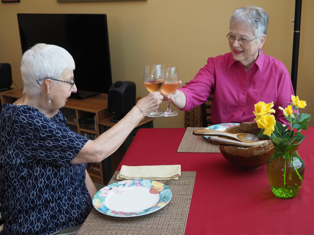 two women clinking wine glasses together