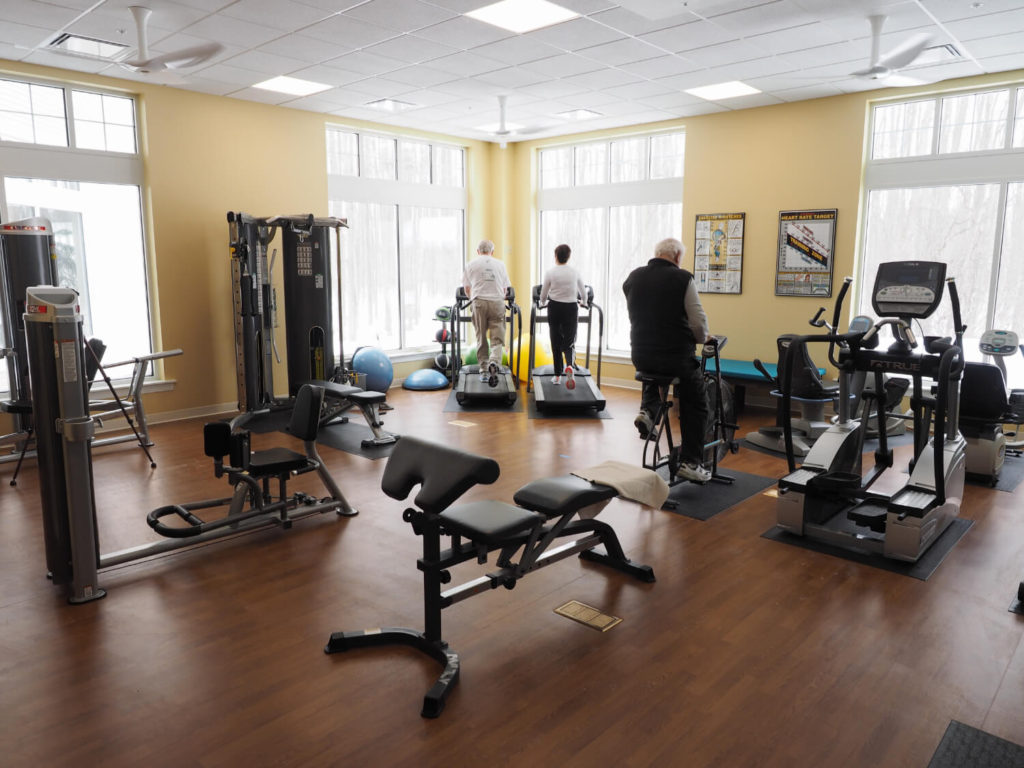 three people working out in fitness room 