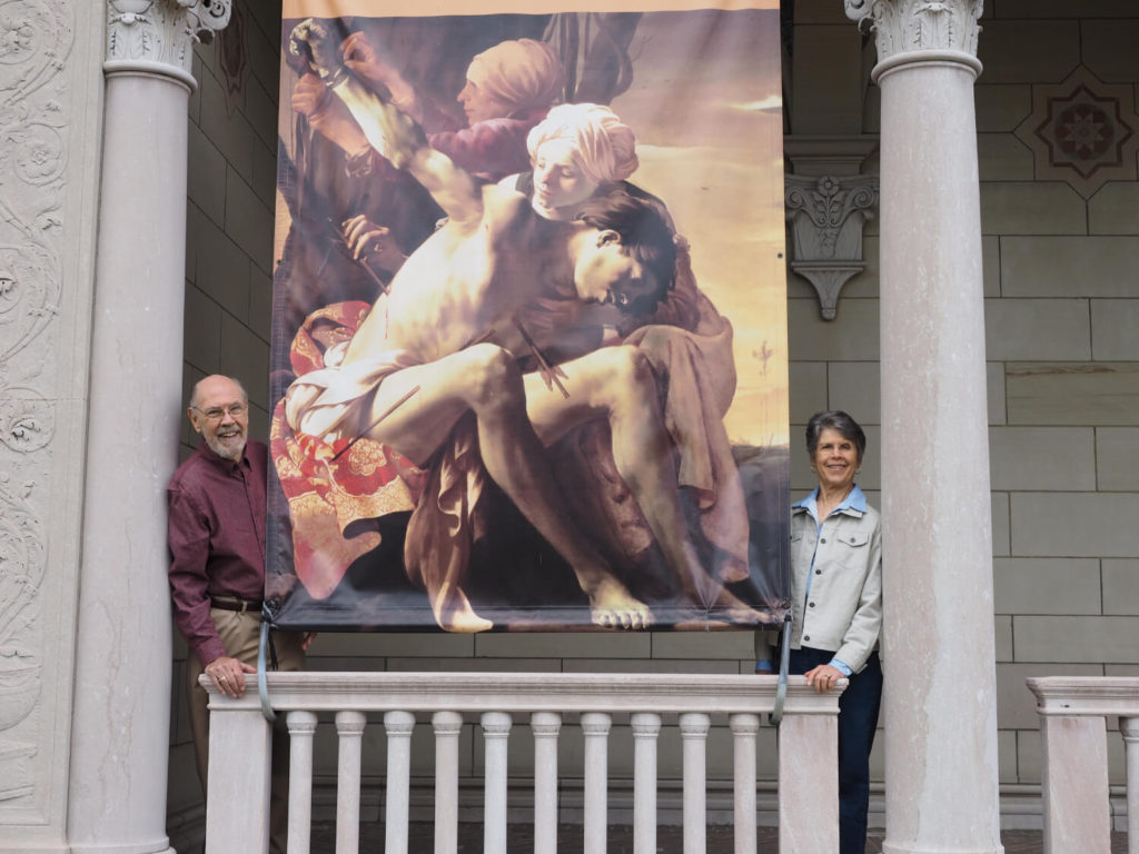 man and woman standing next to museum banner 