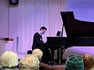 student at piano with audience