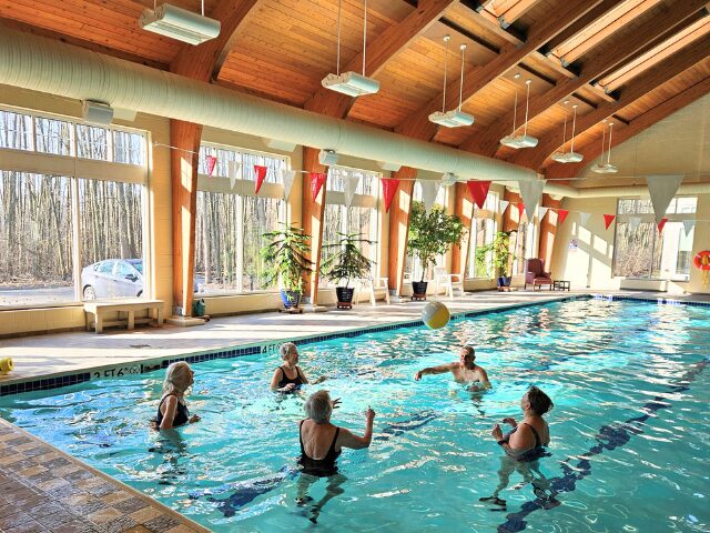 aqua class in pool tossing ball in air 