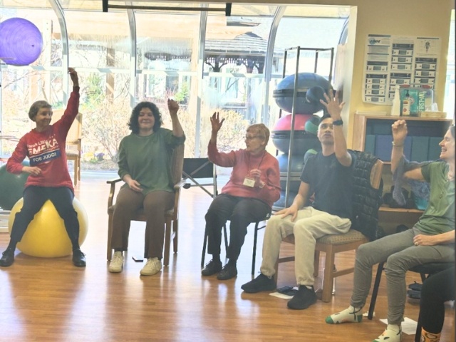 Group sitting in chairs with hands in air