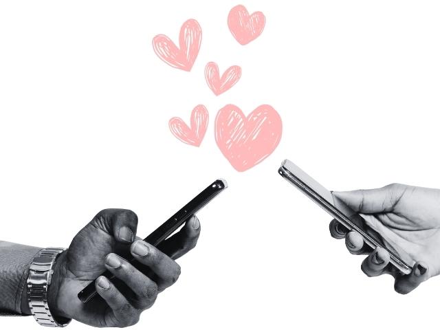 two hands holding cellphones and pink heart graphics in the air